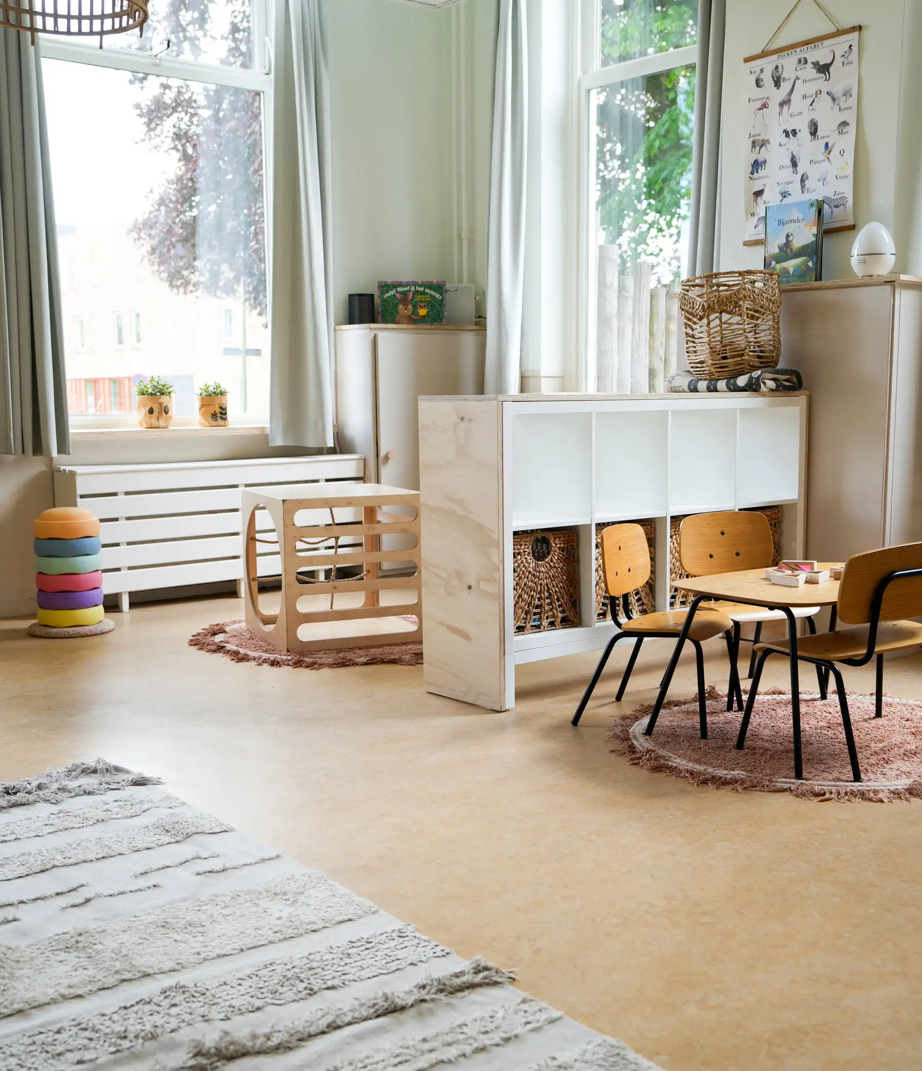 Lichte groepsruimte met kindertafel, stoeltjes en speelmateriaal bij Kideo