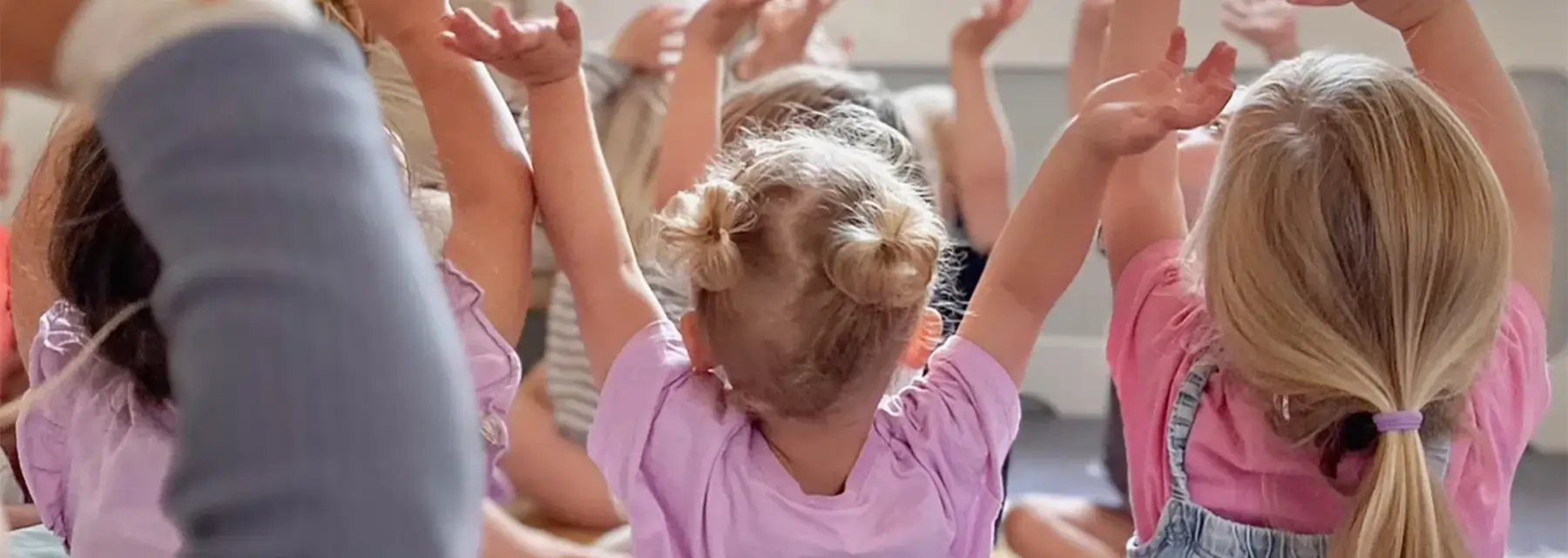 Kinderen steken vrolijk hun handen in de lucht bij Kideo kinderopvang