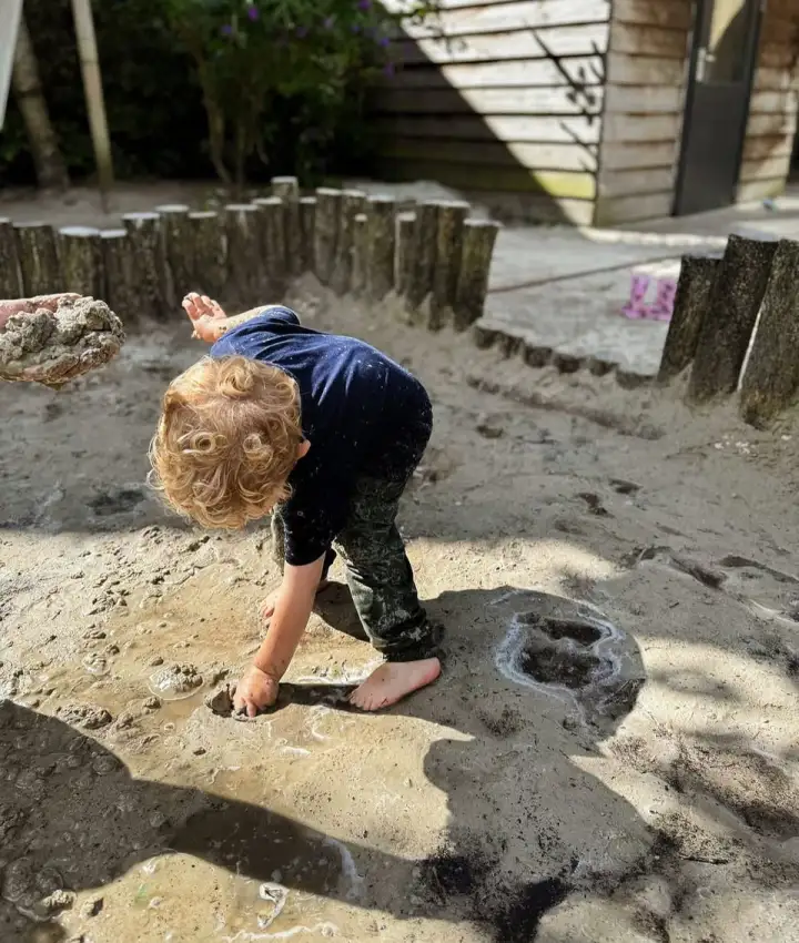 Kind speelt blootsvoets in het zand op de buitenspeelplaats